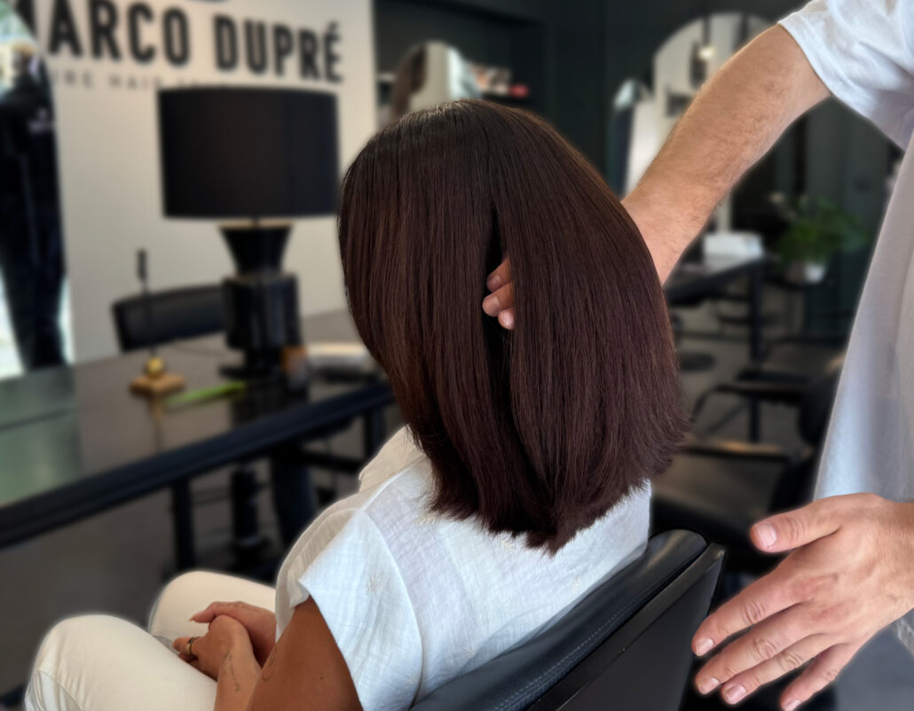 Friseur Marco Dupré prüft per Hand die Haarstruktur einer jungen Kundin